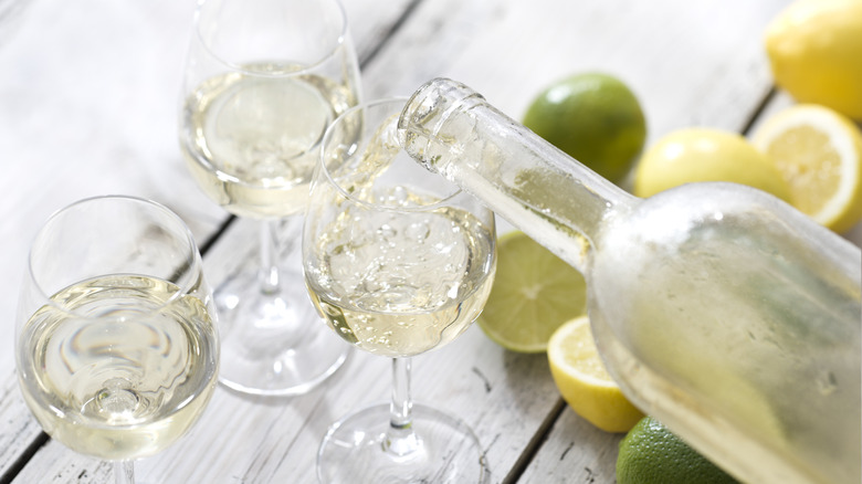white wine being poured and lemons and limes