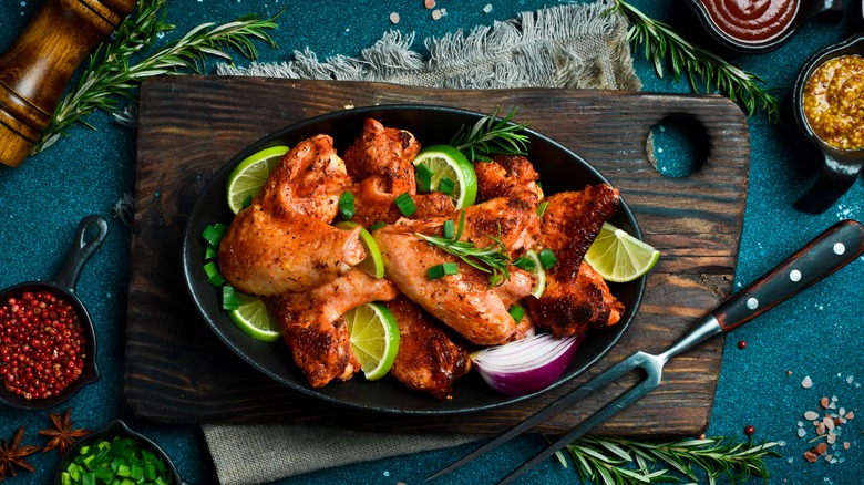 chicken wings on a black plate with lime wedges
