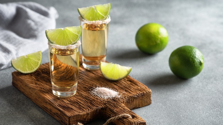 shots of tequila with lime wedges on a wooden board