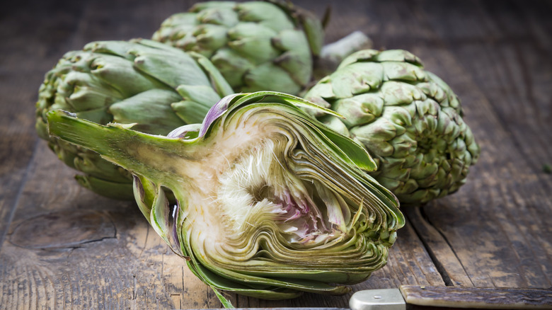 Whole and halved raw artichokes