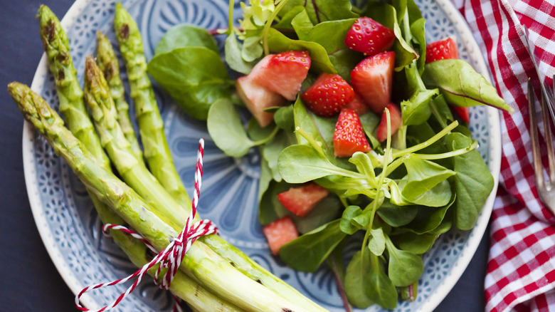 Plate with fresh asparagus, strawberries and spinach