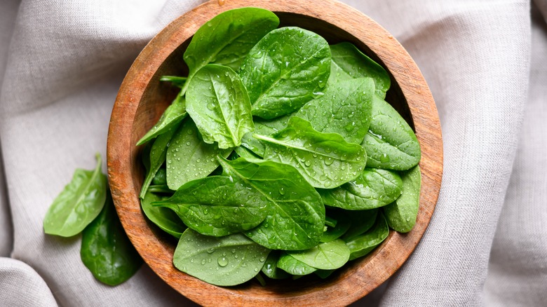 Wooden bowl of freshly washed raw spinach leaves