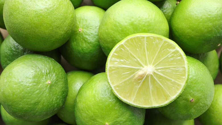 A pile of limes with a cut lime on top