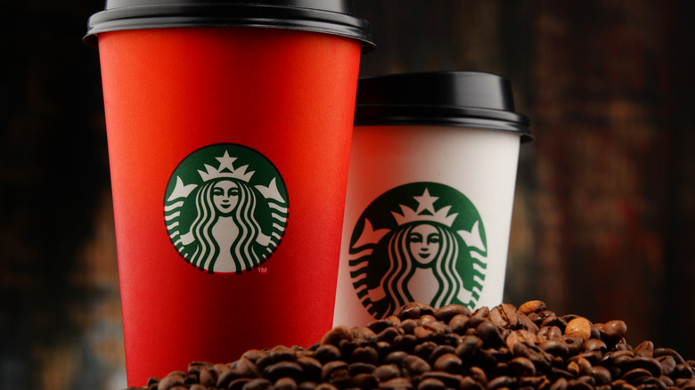 red starbucks cup and normal starbucks drink on coffee beans