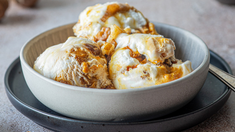 A bowl with three scoops of walnut ice cream sits on a plate.