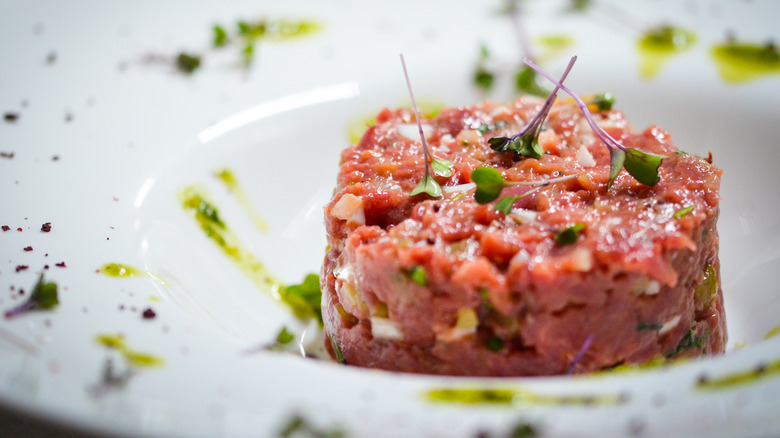 Steak tartare in dish with herbs