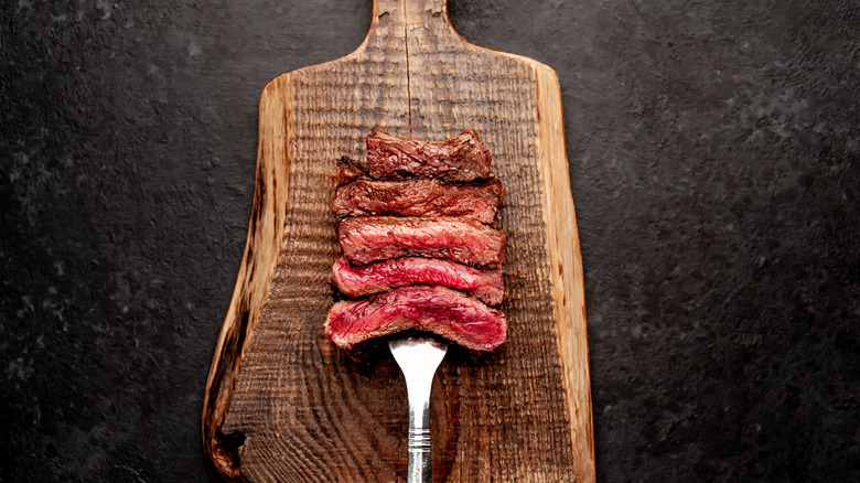 Pieces of steak meat on fork from rare to well done