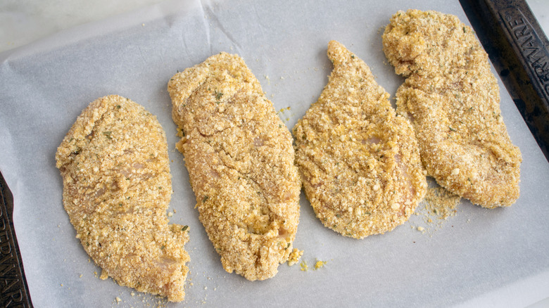 Uncooked breaded chicken cutlets on a baking sheet