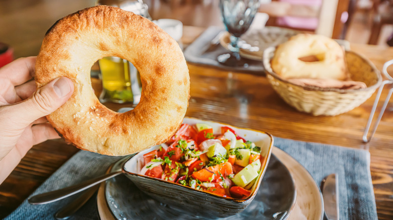 Hand holding a bagel in front of a salad