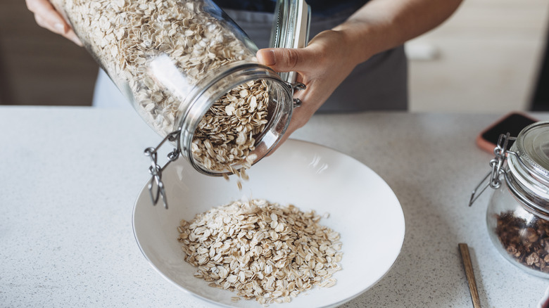 Container of raw oats pouring into bowl