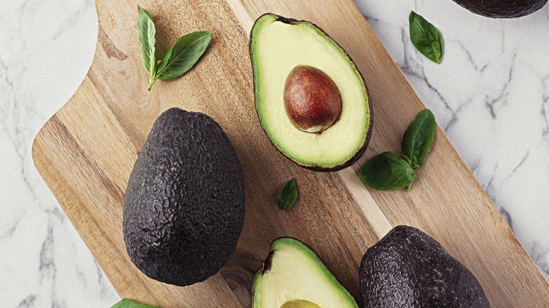 avocados on cutting board with basil