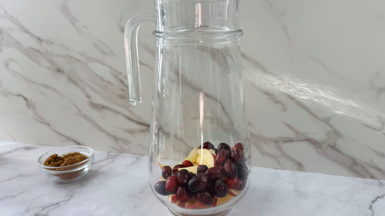 Apples and cranberries in a glass jug on a counter