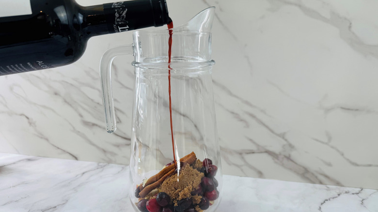 Wine pouring into a jug of spices and fruit