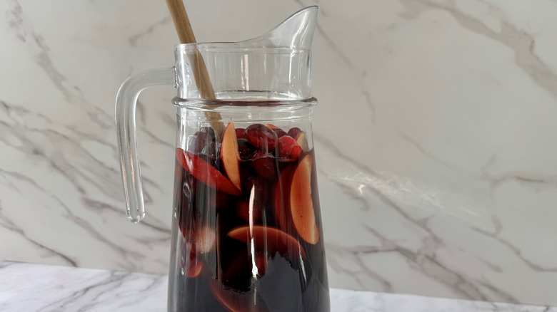 A wooden spoon and sangria in a glass jug