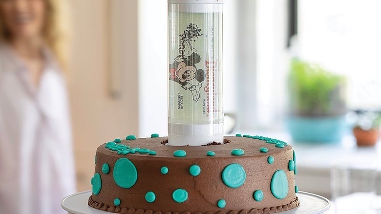 A cake and a cupcake stand with Disney tickets