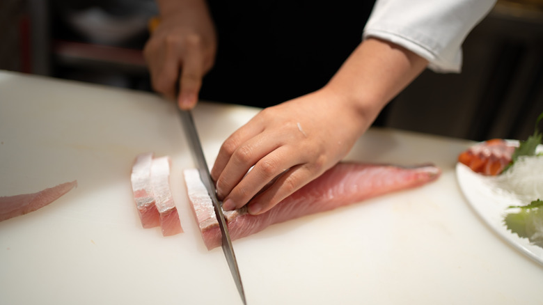 A chef slicing fish for sashimi