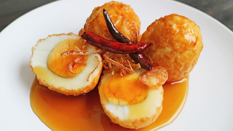 Four deep-fried hard boiled eggs with chili peppers and tamarind sauce