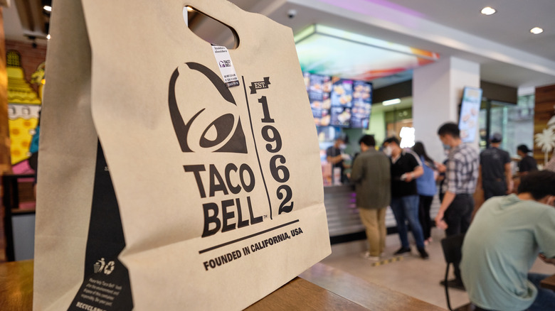 Paper Taco Bell bag on table in crowded restaurant