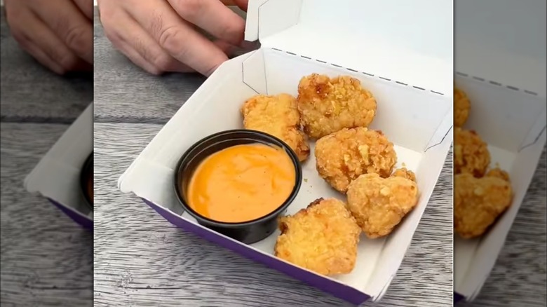 Taco Bell chicken nuggets in box with cup full of orange sauce