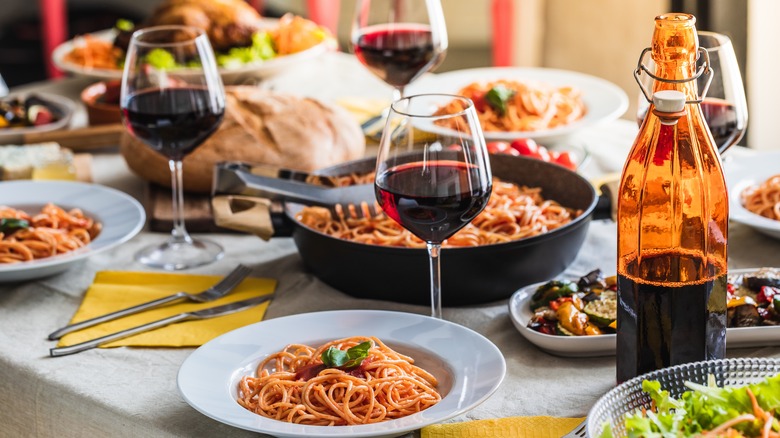 Bowls of spaghetti with tomato sauce with an open bottle of red wine and glasses of wine