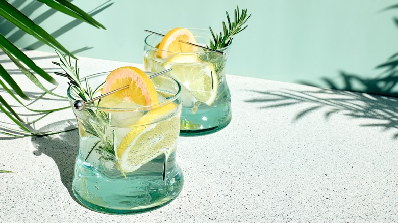 Two cocktail glasses with rosemary and lemons