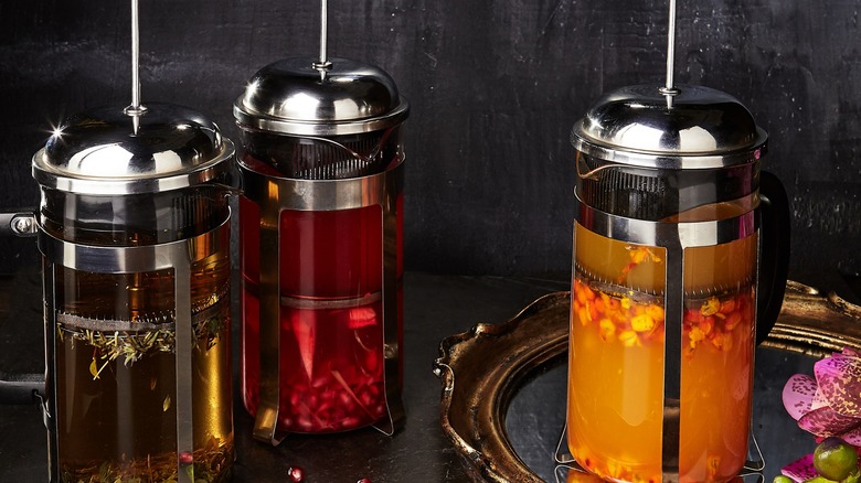 Three French presses with fruit or tea inside