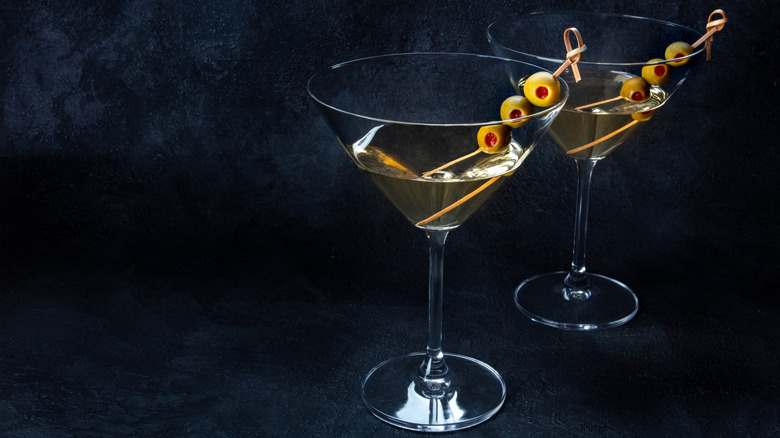 Two dirty martinis garnished with green olive skewers