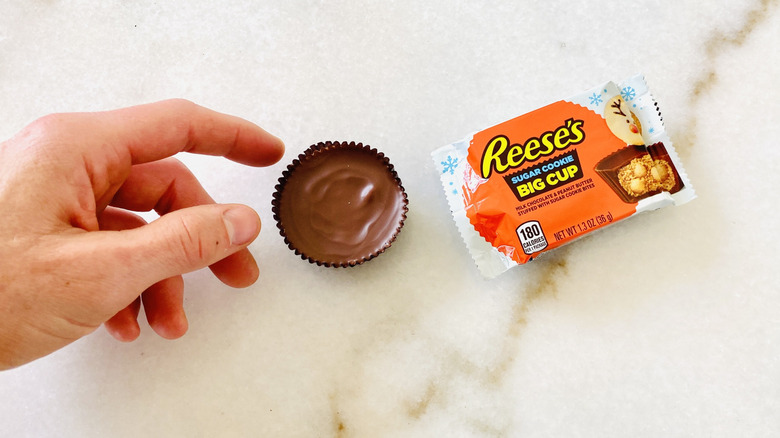 Hand reaching for Reese's peanut butter sugar cookie cup