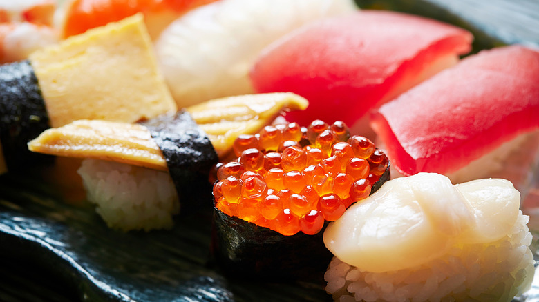 Different types of sushi together on a black plate