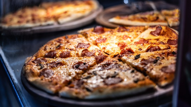 Pizzas displayed under heat lamp