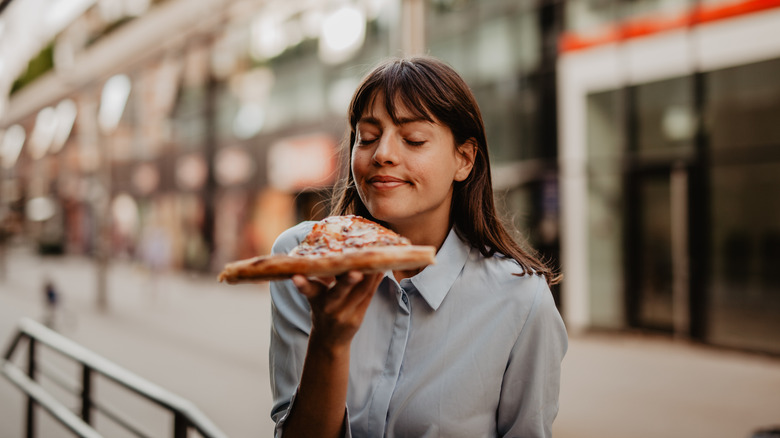 Woman smelling slice of pizza