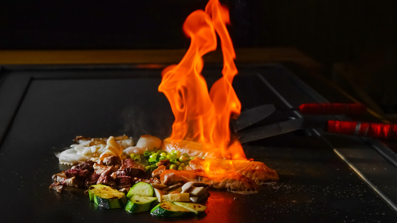 A flaming hibachi grill with meats and vegetables