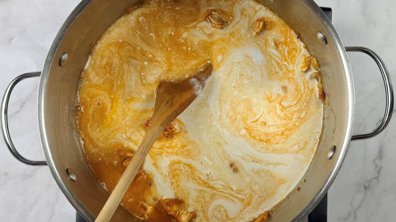 Stirring coocnut milk into soup pot with chicken