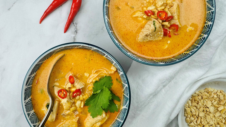 two bowls with Thai peanut soup and garnishes