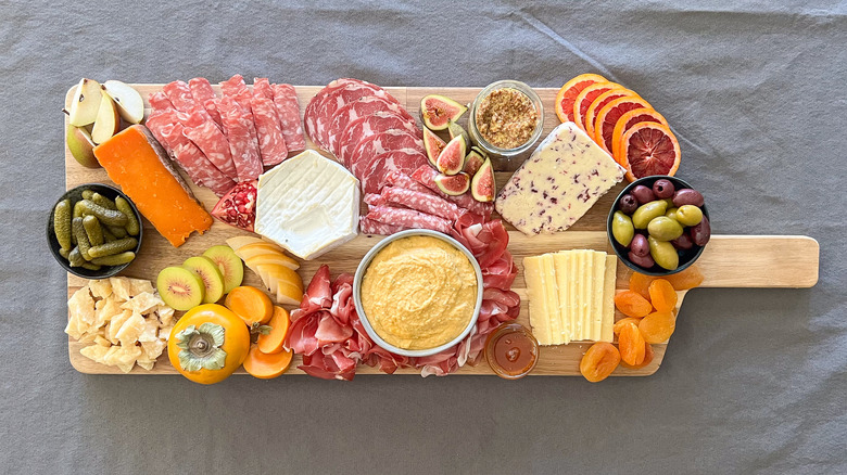 Charcuterie board with assorted cheese, meat, fruits, vegetables and condiments