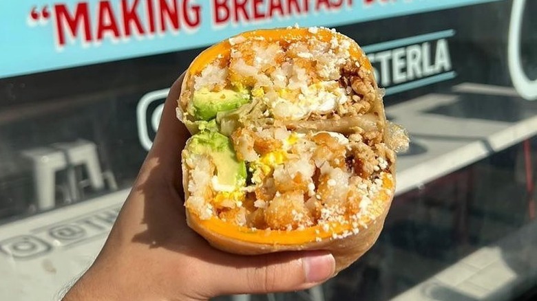 hand holding burrito outside storefront