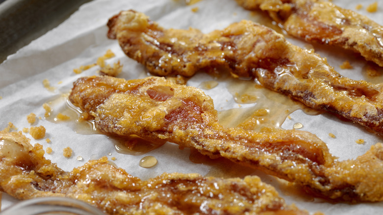 Strips of bacon with candied sugar coating on parchment