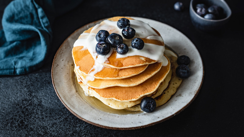 Stack of pancakes with white dessert sauce and blueberries