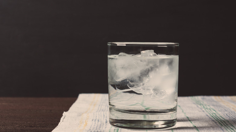 A glass of what could be coconut rum and cream soda resting on a kitchen towel