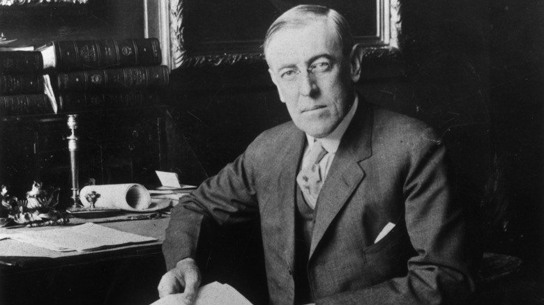 Portrait of Woodrow Wilson sitting at a desk, holding a letter