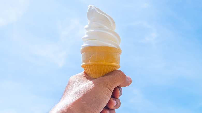 hand holding soft serve ice cream in cake cone