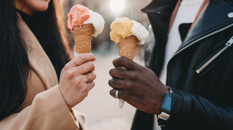 two people holding ice cream in sugar cones