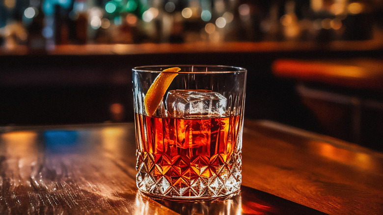 Old Fashioned cocktail with a large, clear ice cube on a bar table