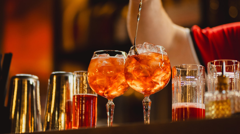 Bartender stirring two spritz cocktails with ice on a bar top