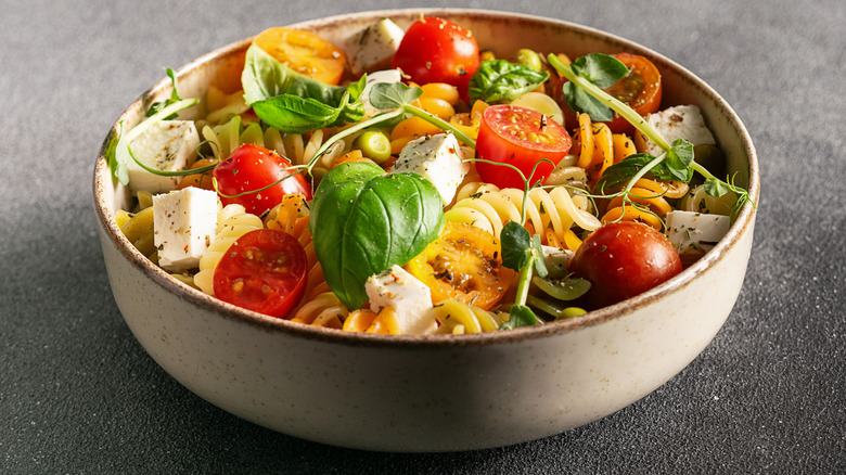 Bowl of colorful pasta salad garnished with herbs