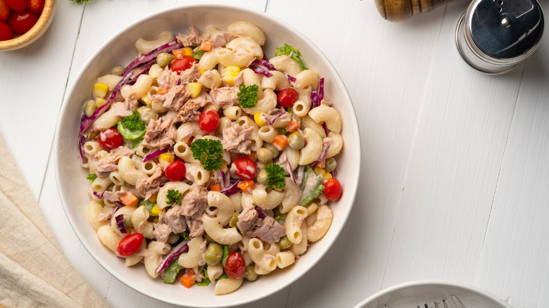 Pasta salad with parsley, tomatoes, red onion, canned fish, corn, and capers