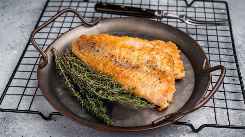 Fried pollock with rosemary on cast iron platter