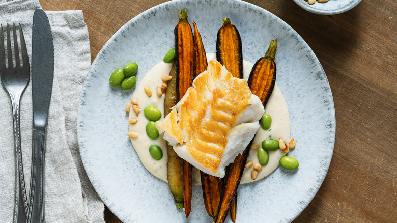 Plate with cod filet and roasted carrots and edamame