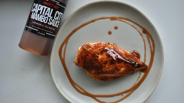 Chicken breast with mambo sauce next to a bottle of Sweet Hot Mambo Sauce