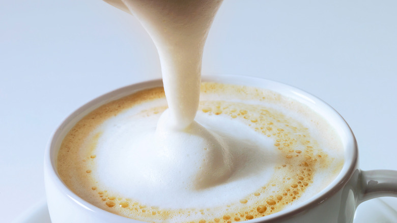 Frothed milk poured onto latte